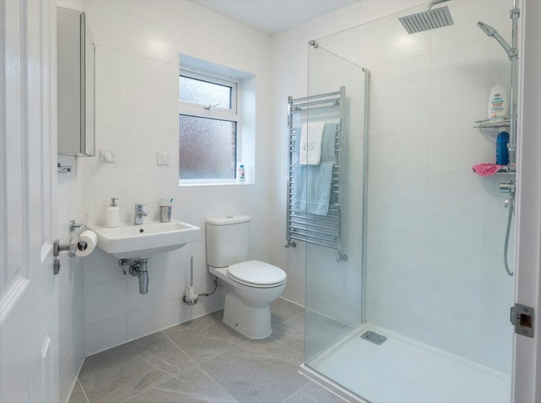 Walk-in shower bathroom with white tiles and grey floor