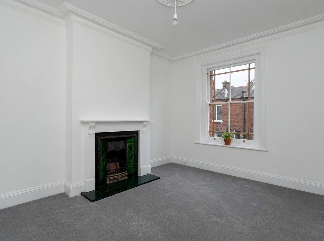 Front room with fireplace, grey carpet and sash window after decorating