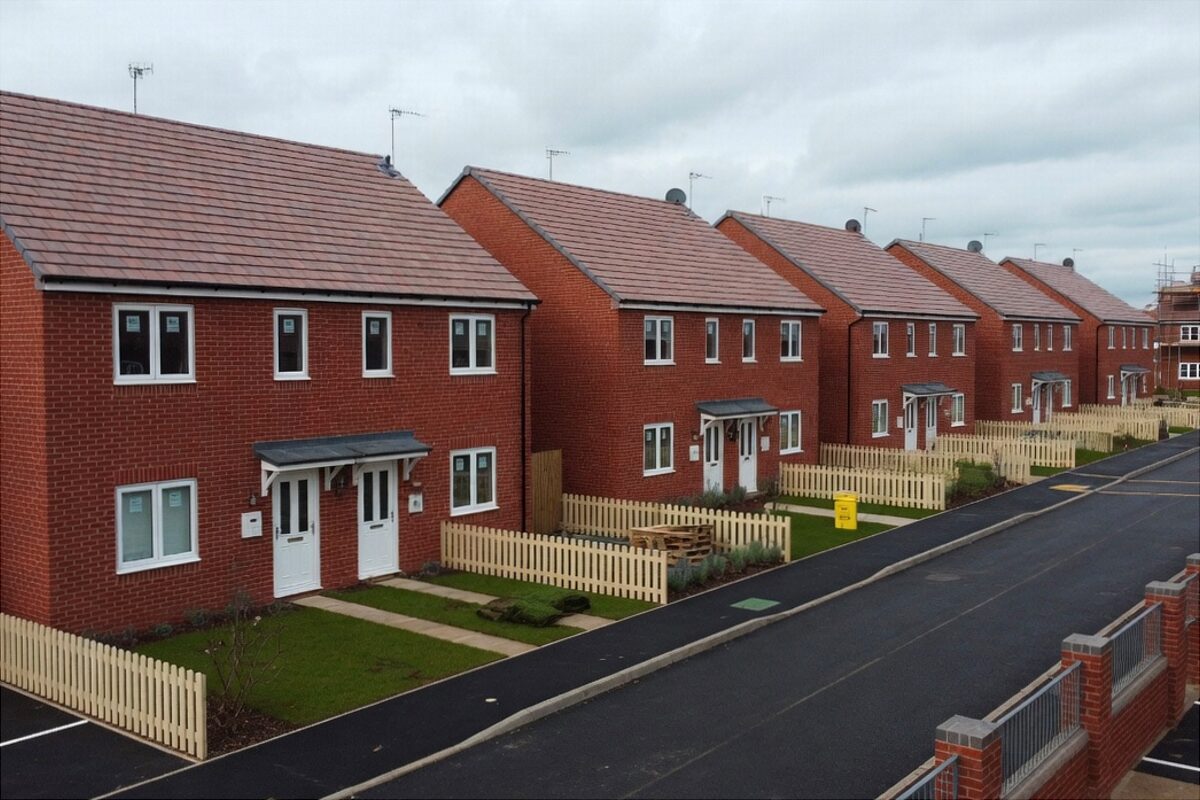 Street of newly completed red-brick houses with tiled roofs and small front gardens